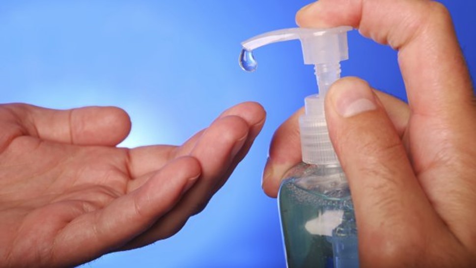 a zoom up of someone hands using a pump bottle of sanitizer