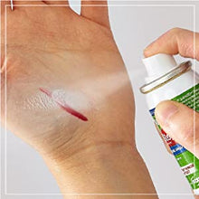 A hand is applying QuickStop! Bleeding Control Spray to a small cut on the palm of the other hand, illustrating the product's direct application for stopping bleeding.
